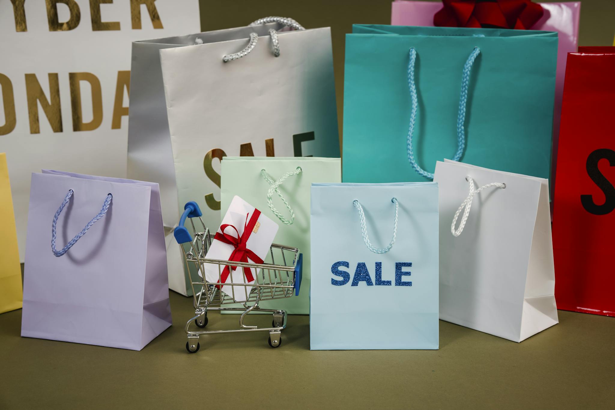 A mix of colorful shopping bags and a small cart displaying a discount gift.