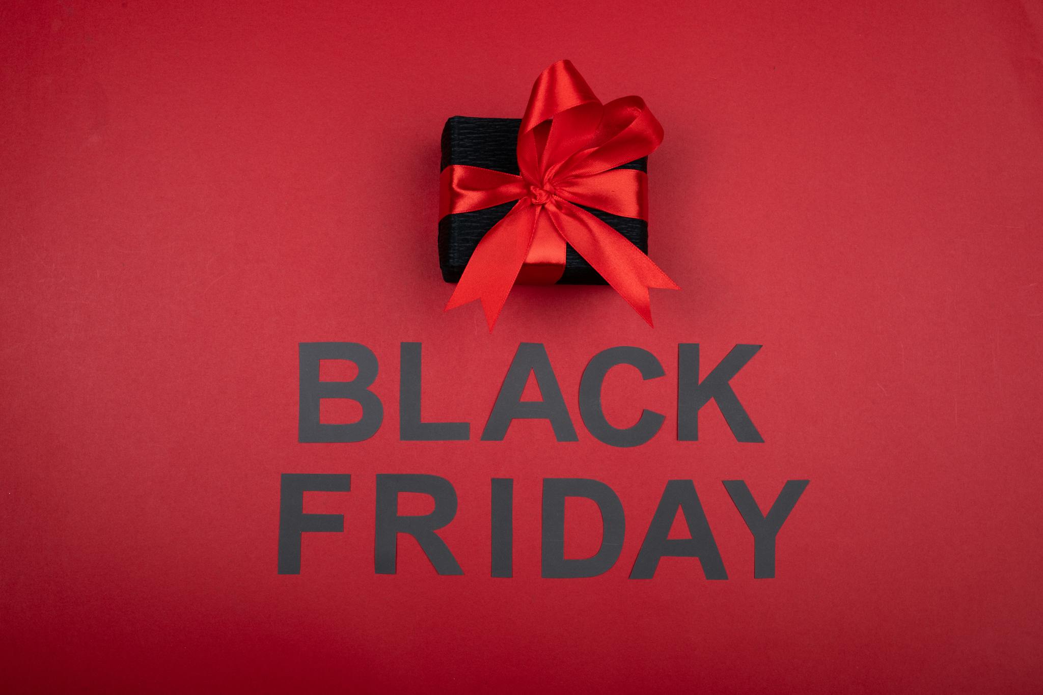 Black gift box with red ribbon, perfect for Black Friday sales promotions.
